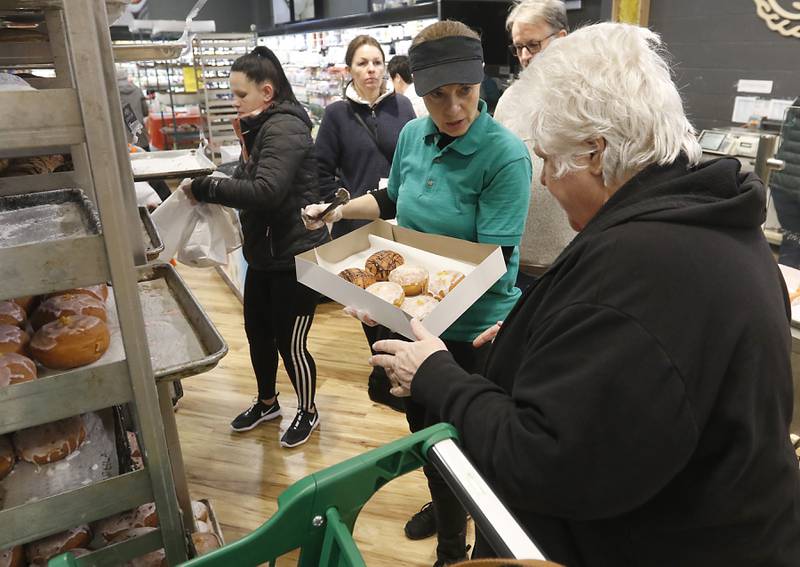 Natalia Chemerys, who works in the bakery department at Deli 4 You in Algonquin, helps  Judy Cleary of Lake in the Hills select paczki Wednesday, Feb, 15, 2023. Area bakeries are prepping for the lead-up to Lent when paczki are traditionally eaten. Deli 4 You will make and sell around 30,000 paczki this week.