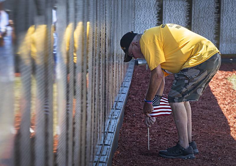 Art Oldham of Tampico plants a flag in front of one of three names of friends Thursday, August 31, 2023 at the Vietnam Traveling Memorial Wall in Rock Falls. Oldham paid respects to friends Ricky Lee Doye, John Fordham and Jerry Celletti, who are all from the area.