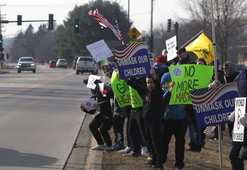 Children hold signs during a Cary School District 26 anti-mask rally Tuesday, Feb. 15, 2022, along Three Oaks Road at Cary-Grove Park. The event was attend by about 100 people and organized by the Illinois Parents Union Cary.