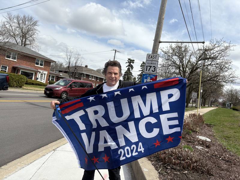Mike Staab of Harvard holds up a flag in support of President Donald Trump and Vice President J.D. Vance April 19, 2025 in Harvard.