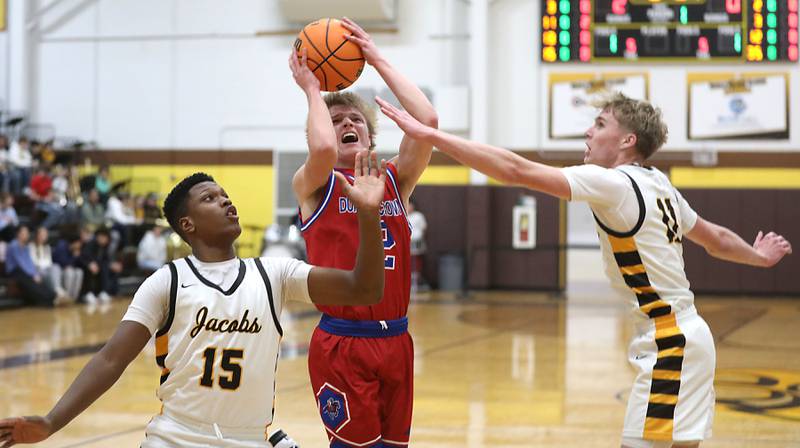 Dundee-Crown's Shane Demarsh shoots the ball between the defense of Jacobs' Chris Williams (left) and Carson Goehring (right) during a Fox Valley Conference boys basketball game on Tuesday, February. 3, 2026, at Jacobs High School in Algonquin.