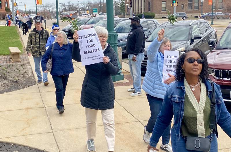 Participants hold signs during a procession at a Palm Sunday Faith Action event on Sunday, March 29, 2026, in front of the DeKalb County Courthouse in Sycamore. Area Christian ministers organized the event to combat the rise of Christian nationalism in the U.S.