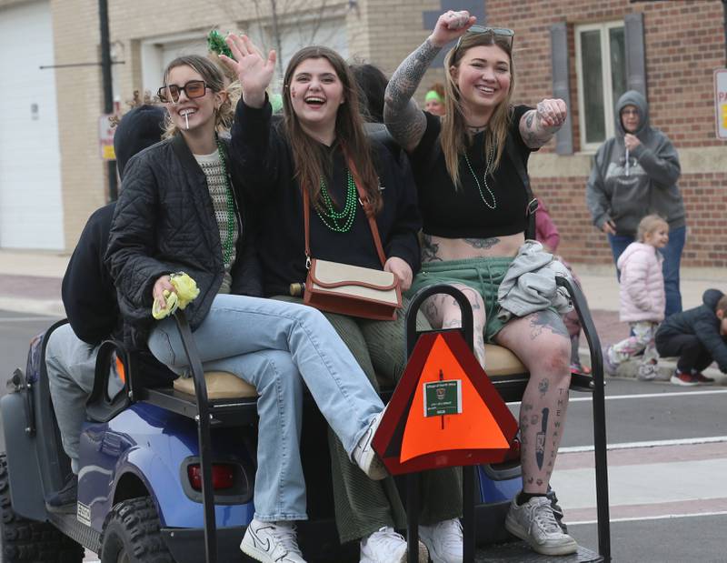 Ladies with the Starved Rock Tattoo Company ride a golf cart during the St. Patrick's Day parade on Saturday, March 15, 2025 downtown Utica.