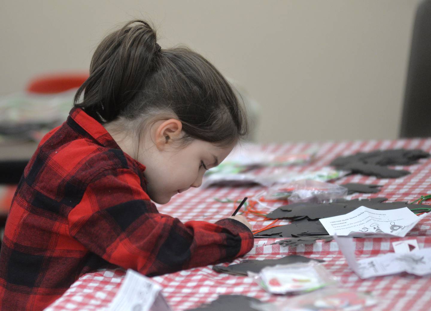 Peyton Lee, 4, of Mt. Morris, works on making an ornament as one of the kids activities during Oregon's Candlelight Walk on Saturday, Nov. 25. 2023. The event included Christmas music, shopping specials, and visits with Santa.