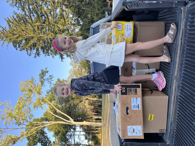 Pictured is Annabelle and Lauren Drozd, daughters of Brittany and Nate Drozd, helping load 19 boxes of donated items onto the collection semi at Zion Lutheran Church in Rockford.