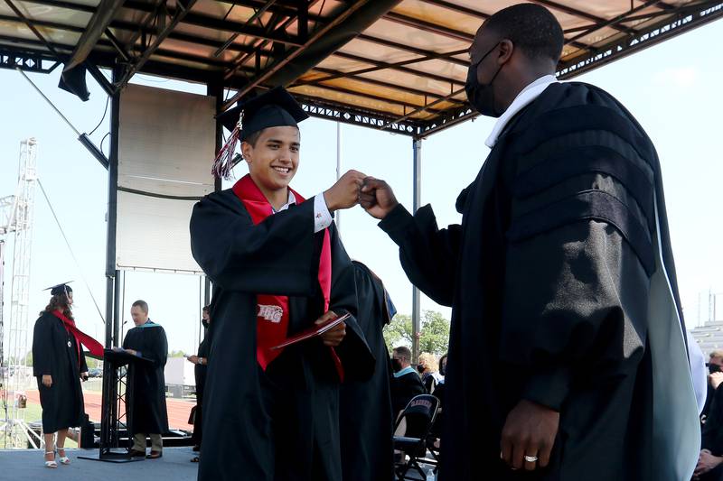 Huntley High School Principal Marcus Belin, right, bumps fists with David Arellano during a graduation ceremony Saturday, May 22, 2021, at the school in Huntley.  The school graduated 736 students over three Saturday ceremonies.