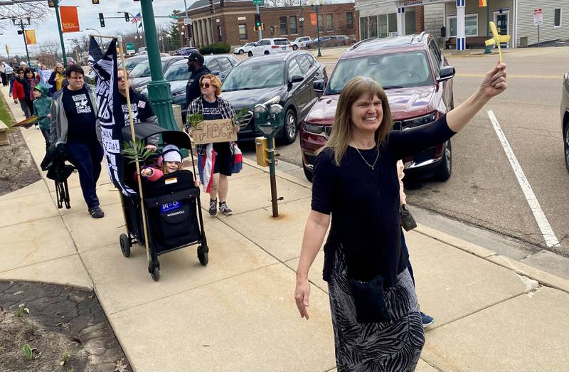 Participants hold signs during a procession at a Palm Sunday Faith Action event on Sunday, March 29, 2026, in front of the DeKalb County Courthouse in Sycamore. Area Christian ministers organized the event to combat the rise of Christian nationalism in the U.S. Participants also held palm branches and other symbols.