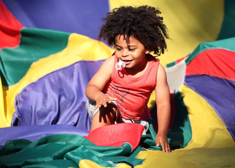 Wyatt Scott, 2, from DeKalb, plays with a parachute Friday, June 14, 2024, during a Dedication Celebration event at Hopkins Park for the grand opening of the new playground and racquet courts.