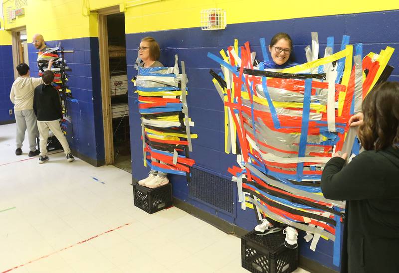 (From left) Science instructor Mr. Andrew Strickler, administrative assistant Mrs. Lori Atilano social studies instructor Rebecca Shepherd are taped to the wall during the "Tape The Teacher" fundraiser on Friday, March 20, 2026 at Logan Jr. High School in Princeton.