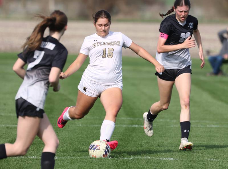 Sycamore's Charlotte Yates kicks the ball between Kaneland's Olivia  Davis (left) and Kaneland's Erin Doucette during their game Monday, April 13, 2026, at Kaneland High School.