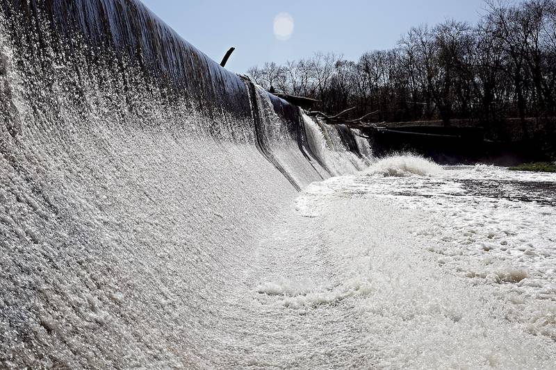 Water from Hickory Creek pours over the Pilcher Park Dam in Joliet on Tuesday.