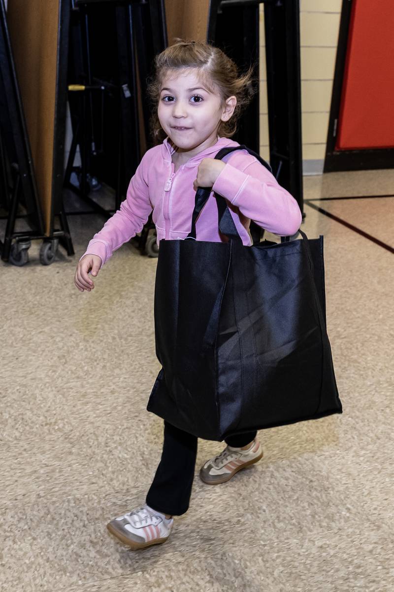 Kindergartener Angelique Munoz carries a bag with a new winter coat from Nicor Gas, in collaboration with Operation Warm, at T. E. Culbertson Elementary School on Nov. 7, 2025.