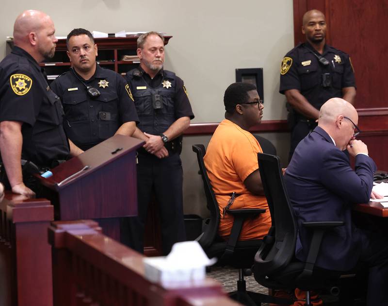 A group of DeKalb County Sheriff’s deputies stand behind Timothy Doll, who pleaded guilty to murdering DeKalb High School freshman Gracie Sasso-Cleveland in 2023, and his attorney Andrew Nickel, Thursday, Aug. 14, 2025, during his sentencing hearing at the DeKalb County Courthouse in Sycamore. Doll was sentenced to 52 years in prison.