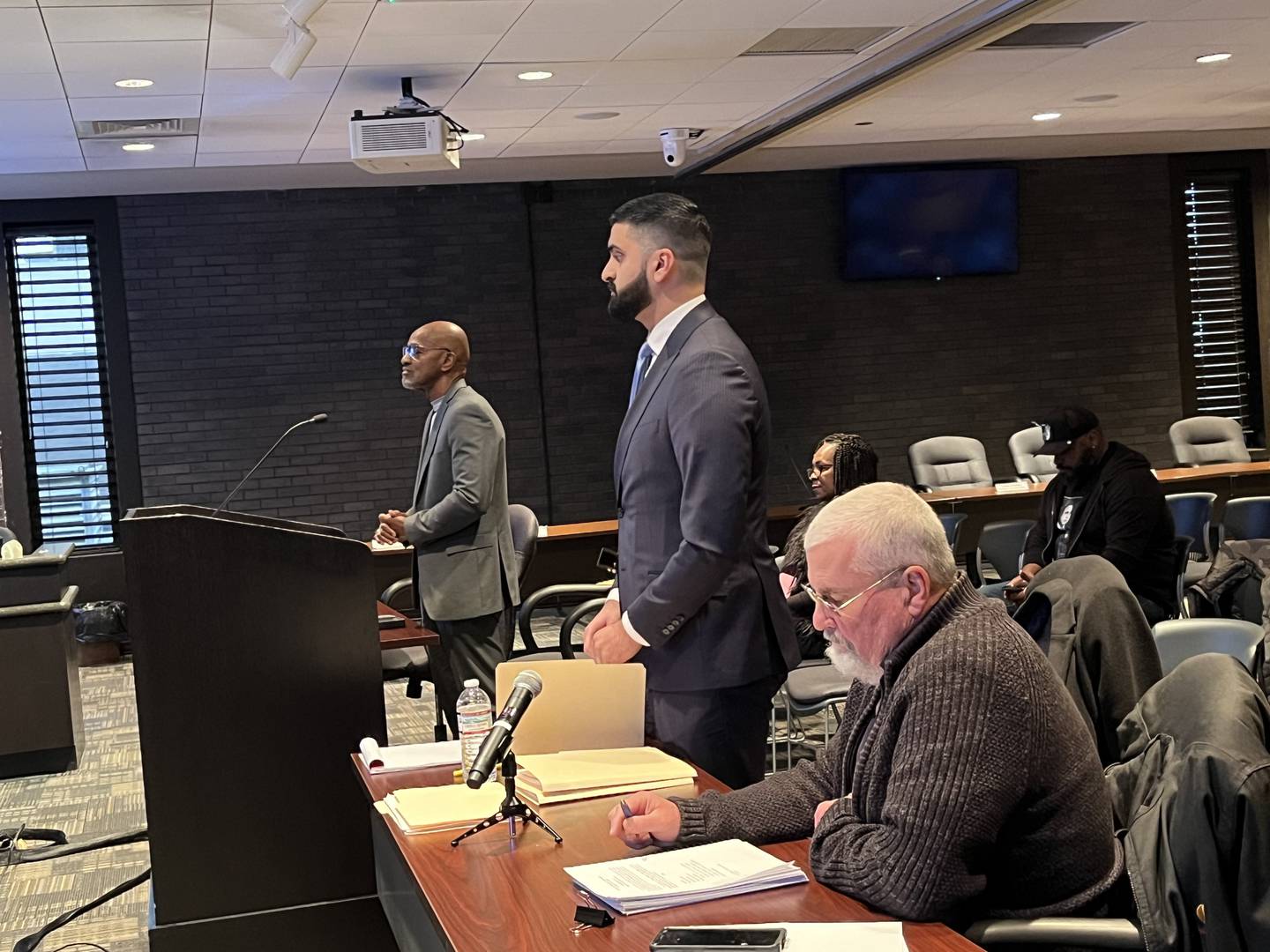 Larry Crawford (left), Chicago attorney Karman Bains and John Dillon, who is seated at a table next to Bains, at the Joliet electoral board hearing on Wednesday, Dec. 11, 2024, at Joliet City Hall.