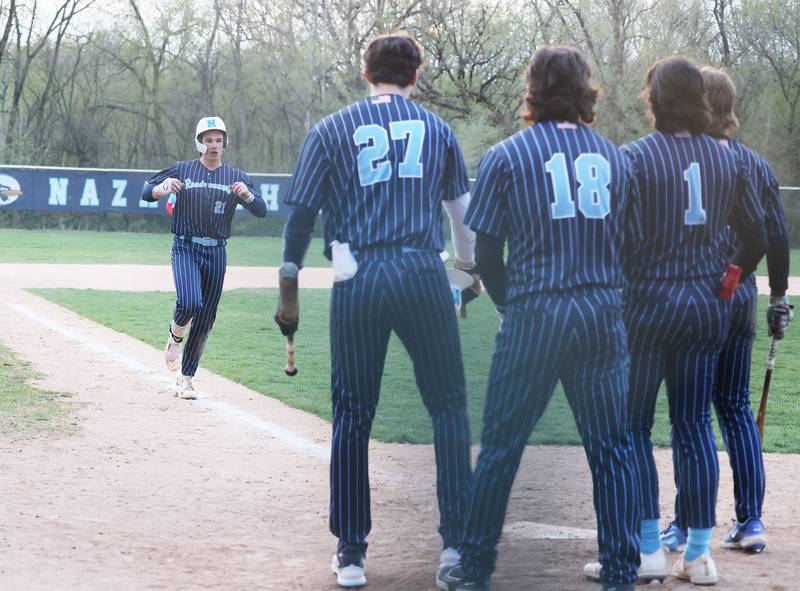 Nazareth's Jaden Fauske approaches home plate and is greeted by teammates after a grand slam home run during the varsity baseball game between Benet Academy and Nazareth Academy in La Grange Park on Monday, April 24, 2023.