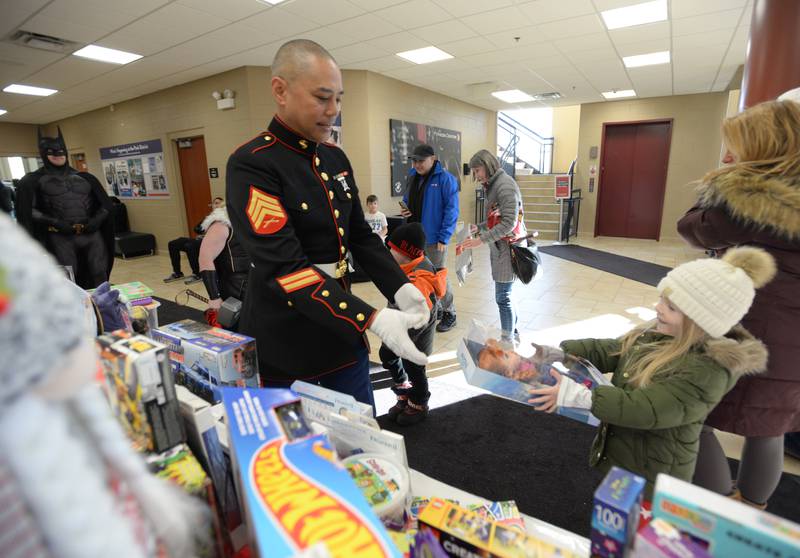 Ava Smevold of Glen Ellyn hands her gifts to Sergeant Roy Pura of Naperville during the Toys for Tots drive held at Ackerman Sports and Fitness Center Sunday Dec 4, 2022.