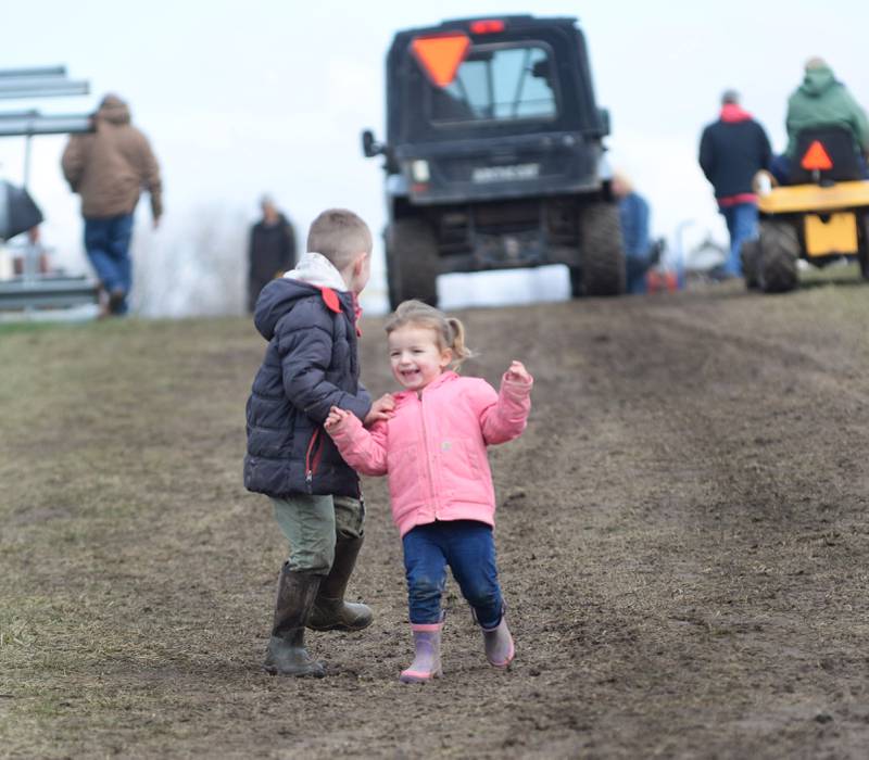 Aubrey Ebersole, 2, runs down a muddy hill with Kyson Nausbaum, 5, of Sterling while attending the Hazelhurst Spring Consignment Auction with their family on Saturday, April 5, 2025.