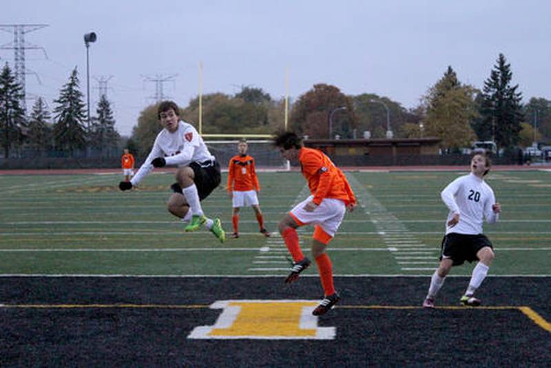 Chris Day (left) protects the Minooka goal against Edwardsville player Josh Kowalis in the sectional final Friday. The Indians lost, 4-0, ending their season.