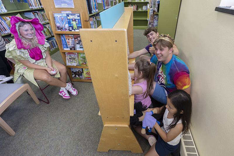 Petunia Attendant Owen Winters (right) and King Tyler Zepezauer cram in beside Lainey Hey, 7, and Chella Hey, 5, for a puppet show Wednesday, July 3, 2024 at the Dixon library.