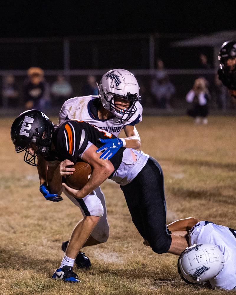 Logan Ruddy (12) of FCW runs ball as (top) Blake Janson (1) of Ridgewood and teammate (bottom) Crew Roberson (22) tackle him to floor on Friday, Sept. 26, 2025, at Woodland School in rural Streator.