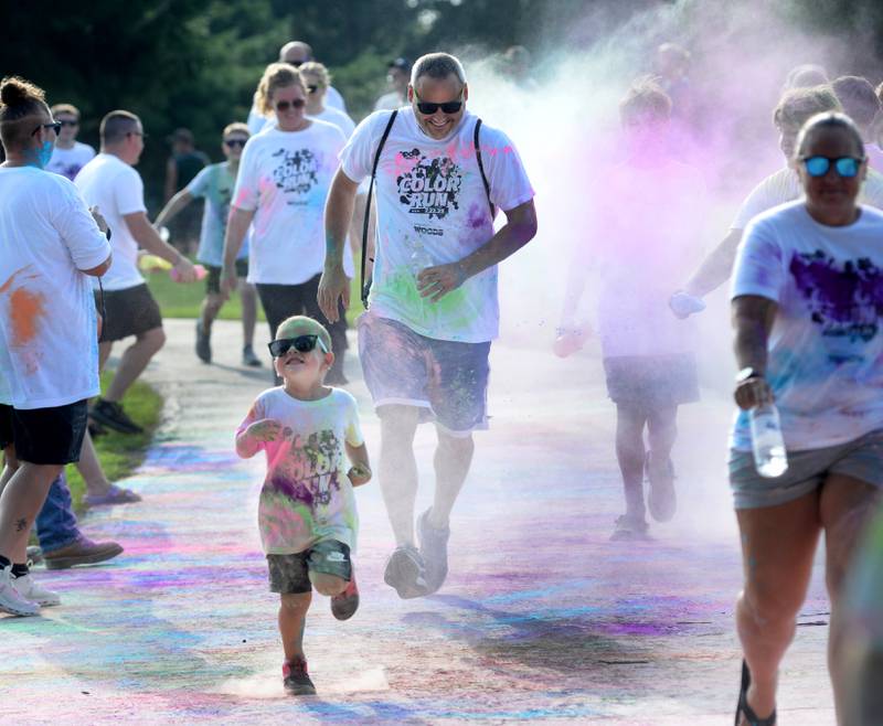 Adam Albrecht of Oregon follows his son through a cloud of powder during the Oregon Park District's Color Run on Tuesday, July 22, 2025. The popular event had close to 400 people take part at Park West.