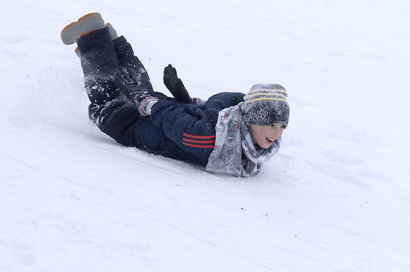 Brody Perocho, 8, of Crystal Lake, slides down the hill without a sled at Veteran Acres Park the afternoon of Monday, Jan. 24, 2022, after McHenry County received a fresh snowfall.