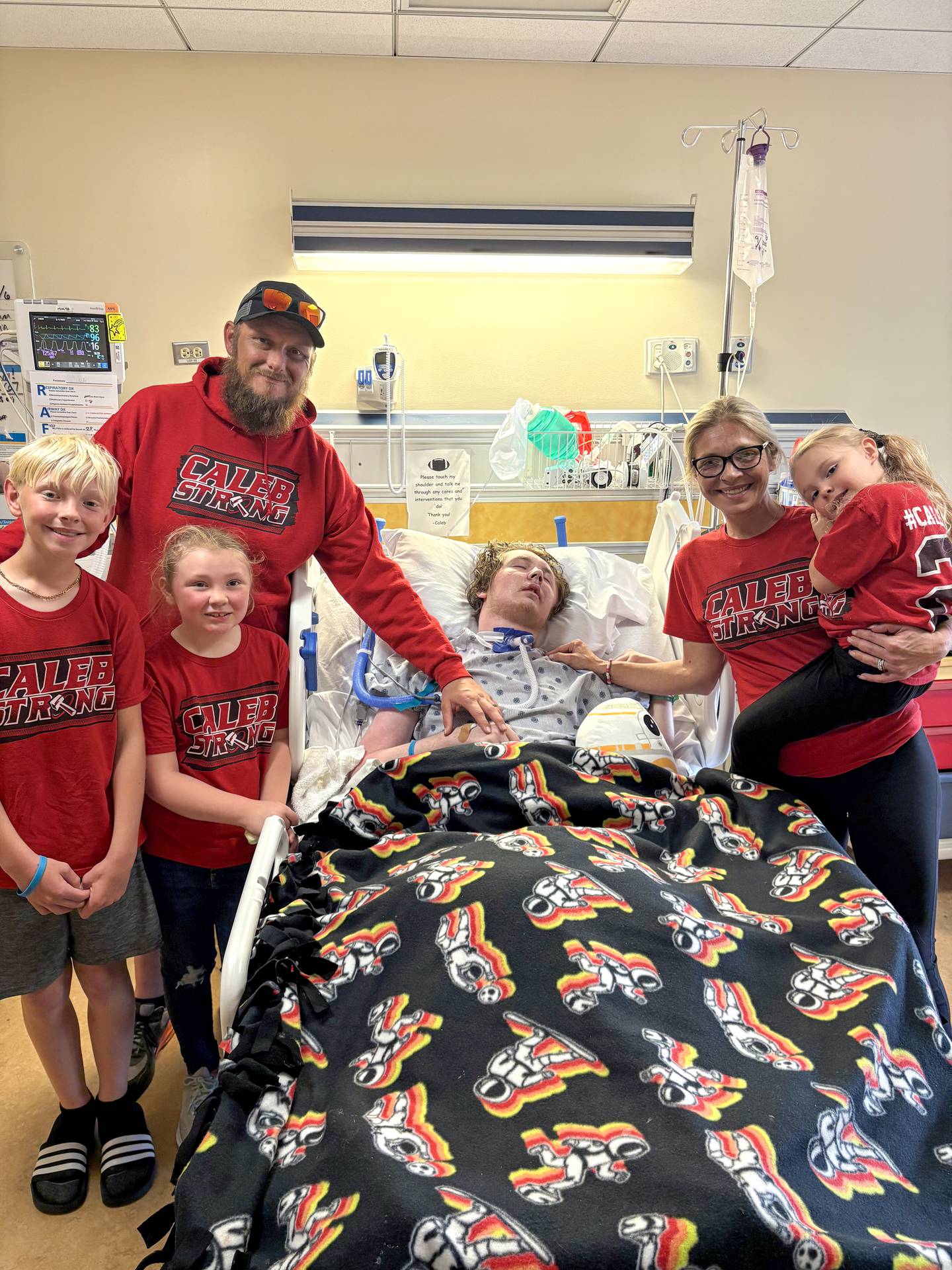 Jennifer and Nick Outerbridge and their three youngest children, Noah, 11, Ella, 8, and Gracie, 5, pose for a photo with their oldest son Caleb, now 17, at the hospital in September. Caleb, who suffered a rare autoimmune disease just before last Thanksgiving that rendered him unconscious, has been making progress as he heals from brain injury caused by the disease.