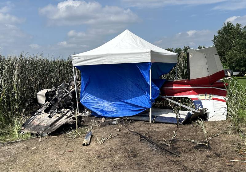 The charred remains of a crop dusting plane lies upside down in the edge of a cornfield on along Illinois Route 64 near the Ogle County Airport between Oregon and Mt. Morris on Tuesday, July 22, 2025. The pilot of the plane was killed after hitting power lines near the airport. A section of Illinois Route 64 remained closed between Rock and Ridge roads as ComEd crews worked to repair damage to poles and lines. This photo was taken after the pilot was removed from the wreckage.