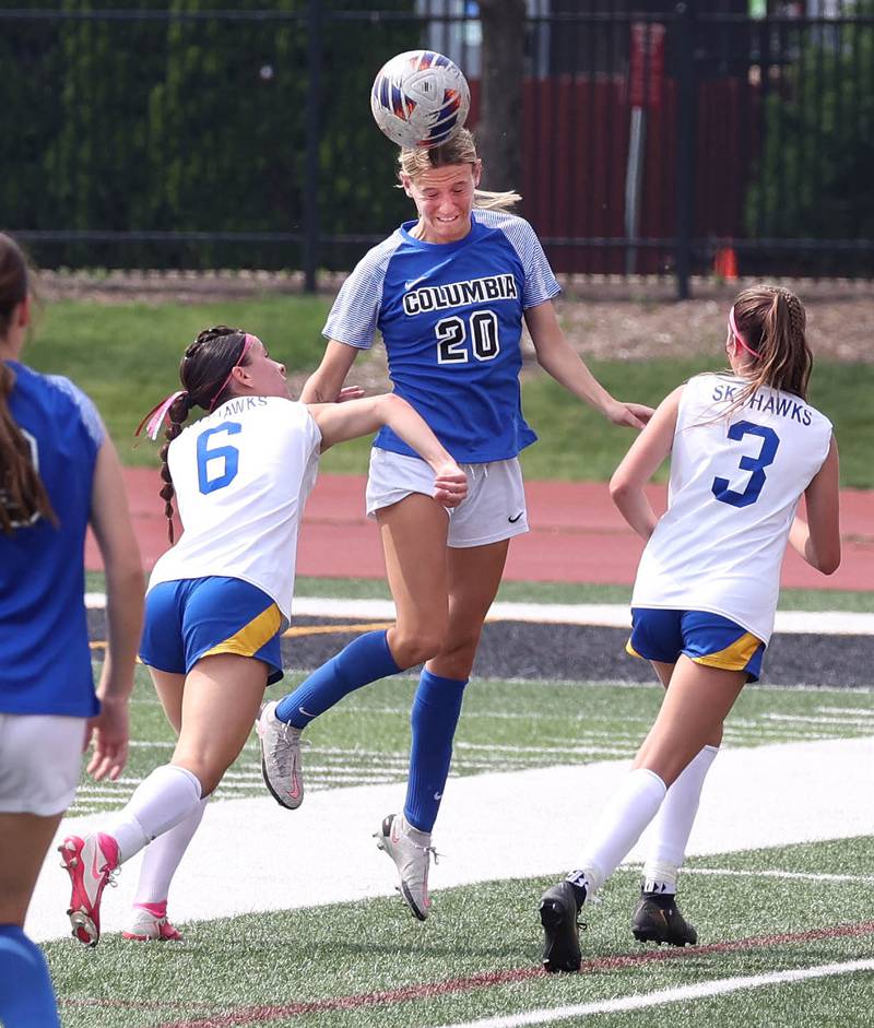 Columbia's Sam Schmuke heads the ball between Johnsburg's Liz Smith and Charlie Eastland Saturday, June 7, 2025, during the IHSA Class 1A state championship game at North Central College in Naperville.