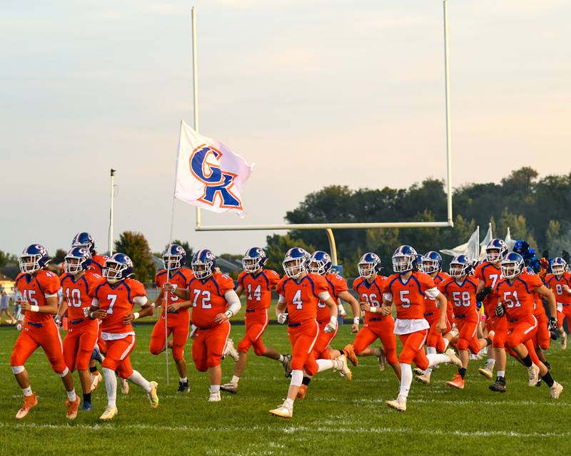 Genoa-Kingston Colton Hinds (72) carries a flag as the varsity team takes the field for warmups on Friday Sep. 16th while they take on Byron at Genoa-Kingston.