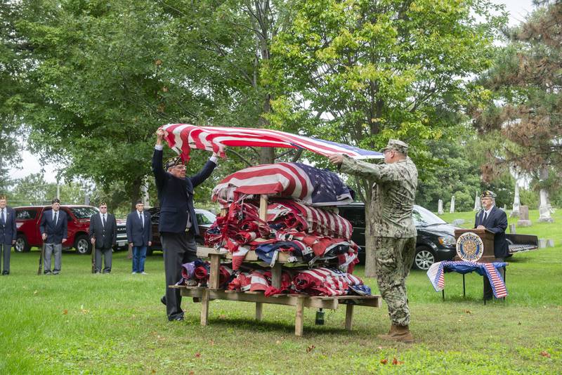 Morrison American legion commander Larry Zuidema (left) and senior vice commander Dennis VanZuiden, drape a retired flag over 597 others during a ceremony Sunday, Sept. 25, 2022 in Morrison.
