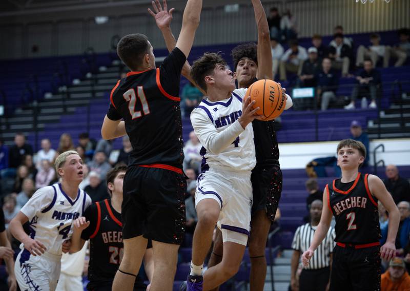 Manteno's Cade Bechard, center, makes a drive toward the net as Beecher's Michael DeFrank, left, and Wences Baumgartner, right defend in the Thanksgiving tournament at Manteno High School on Monday, November 24, 2025.