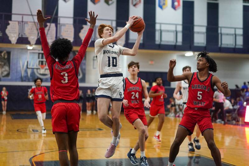 Oswego East's Noah Mason (10) drives to the hoop against West Aurora's Jayvyn Marion (3) and Terrence Smith (5) during a basketball game at Oswego High School on Friday, Feb 2, 2024.