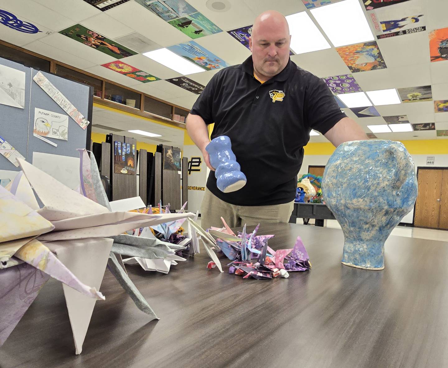 Putnam County High School art teacher Joshua Curry prepares Friday, May 2, 2025, for the Hazel Marie Boyle Fine Arts Festival by putting on display students' artwork.