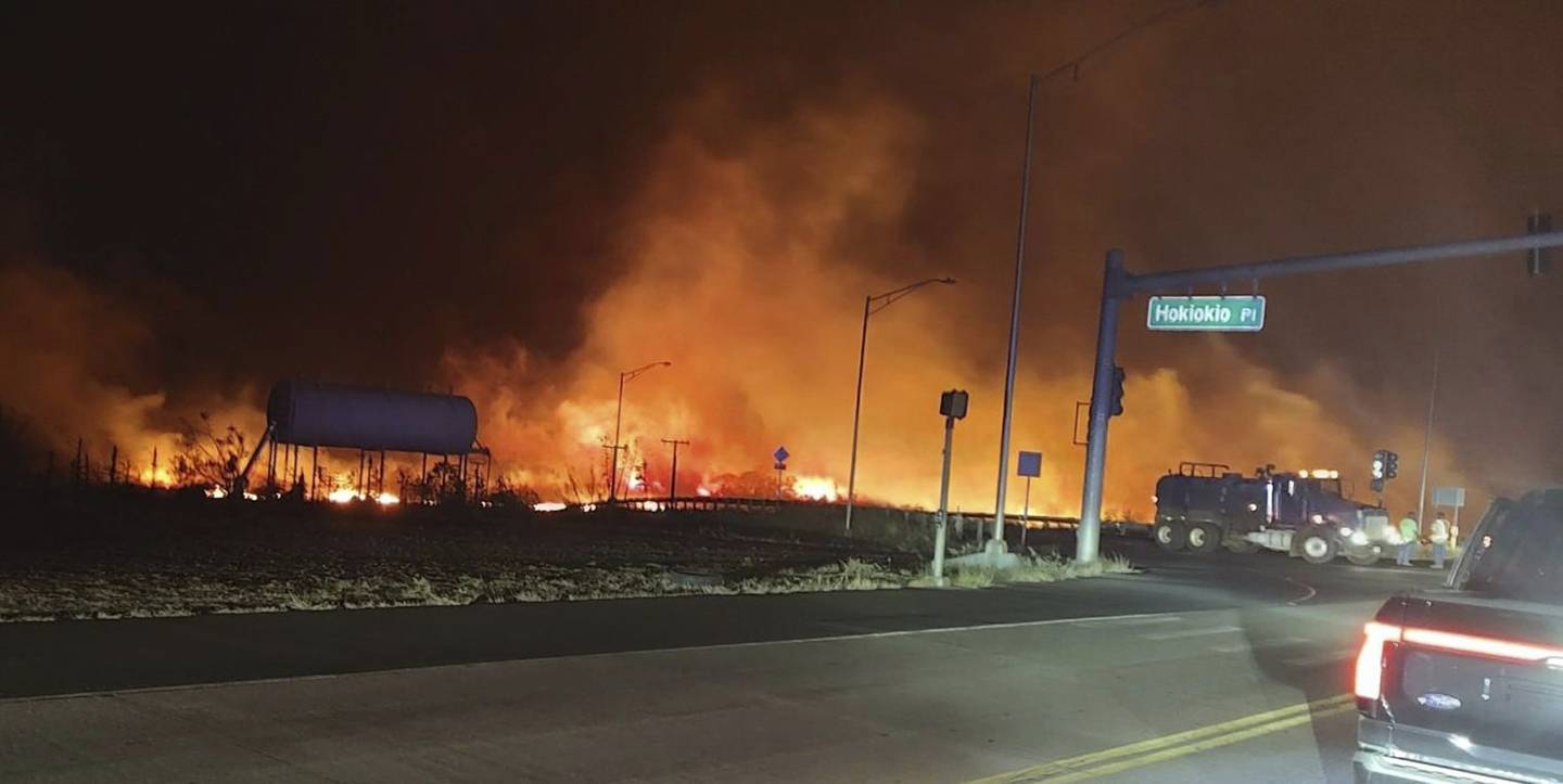 This photo provided by County of Maui shows fire and smoke filling the sky from wildfires on the intersection at Hokiokio Place and Lahaina Bypass in Maui, Hawaii on Tuesday, Aug. 8, 2023. Wildfires in Hawaii fanned by strong winds burned multiple structures in areas including historic Lahaina town, forcing evacuations and closing schools in several communities Wednesday, and rescuers pulled a dozen people escaping smoke and flames from the ocean.