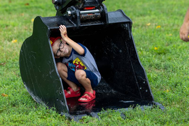 Graham Wright sits inside a bucket of an excavator at the Touch a Truck event on Sunday, July 27, 2025, at Riverfront Park in Ottawa.