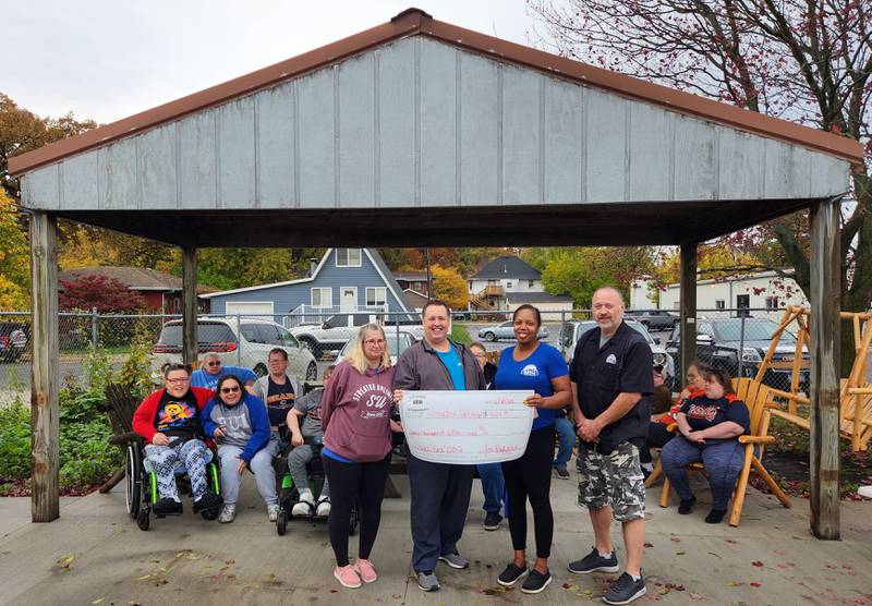 Dig Doug's Backyard BBQ Raffle raised $4,000 for Streator Unlimited. Marla Merritt, John Mallaney, Joi Ruffin and Doug Allen pose with a check in front of Streator Unlimited consumers enjoying the new concrete flooring.