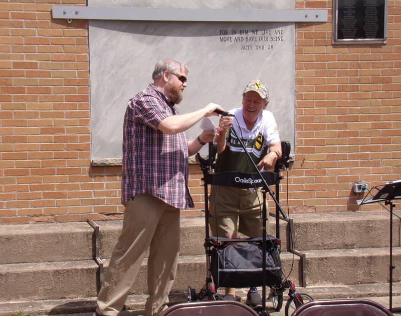 Pastor Ben Webster of Streator Central Church of Christ assists Ron Sauers, emcee, Monday, May 27, 2024, during the Memorial Day ceremony at Veterans Memorial Plaza in Streator's City Park.