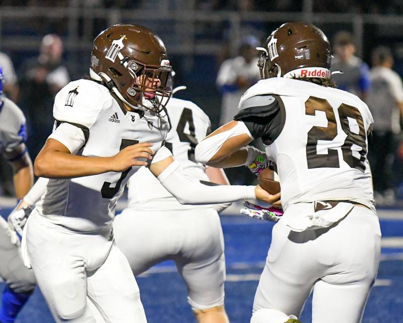 Joliet Catholic Academy’s Andres Munoz, left, hands the ball off to teammate Nate Magrini (28) during the second quarter on Friday Sep. 22, 2023, while traveling to take on St. Francis in Wheaton.