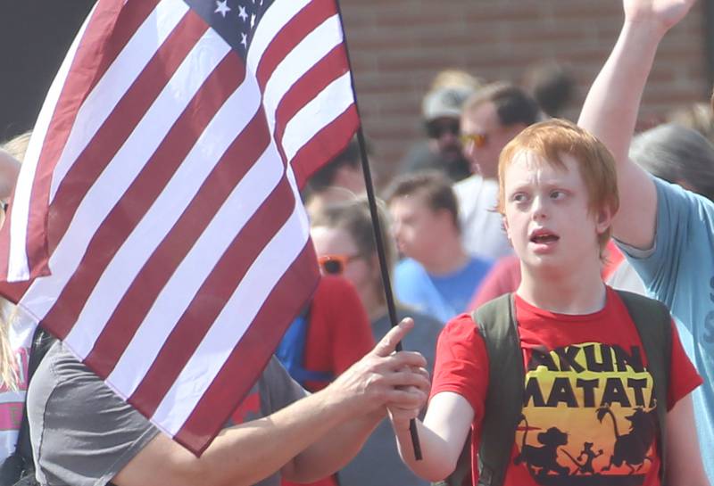 Lighted Way student Nathan Bauer carries the American Flag around the track during the Lighted Way and Trinity Catholic Academy PALS Spring Track Meet on Monday, May 13, 2024 at the L-P Athletic Complex in La Salle. Lighted way students participated in running, throwing, wheelchair slalom and much more.