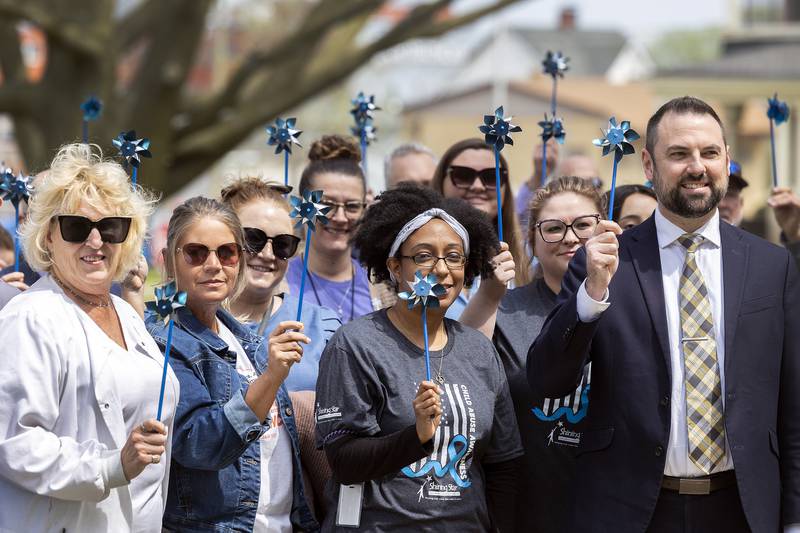 Approximately 100 people attend “Hands Around the Courthouse” Friday, April 25, 2025, to bring attention to Child Abuse Prevention Month. The blue pinwheel is a national symbol of child abuse prevention.