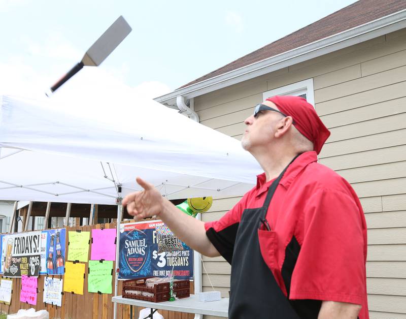 Mike Armintrout flips his grilling flipper in the air while making burgers outside the 9th Street Pub for St. Margaret's Healthcare workers on Friday, June 16, 2023 in La Salle.