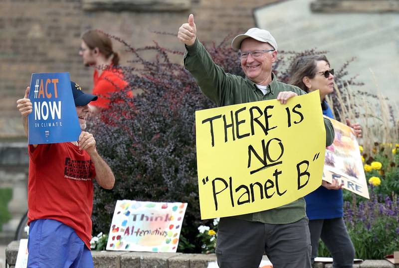 Alfred Mueller, from Sycamore, gives a thumbs up to a passing motorist who honked their horn during a rally Saturday, Sept. 16, 2023, at Memorial Park in downtown DeKalb. The demonstration was held to push legislators to promote alternative forms of energy and lessen the use of fossil fuels.