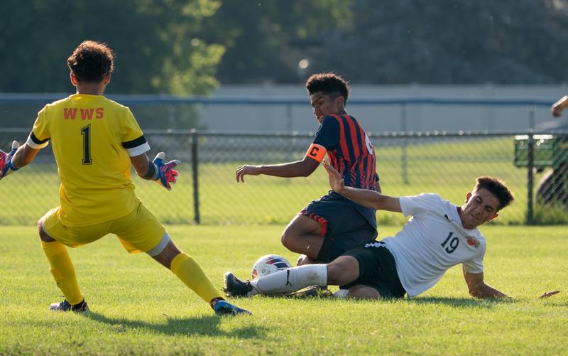 Wheaton Warrenville South's Nikhil Bawa (19) defends the box with a slide tackle against Oswego’s Salvador Martinez (6) during a soccer match at Oswego High School on Thursday, Aug 25, 2022.