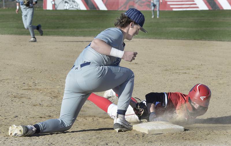 Streator baserunner Zander McCloskey dives back into the first-base bag as Plainfield first baseman Daniel McCauley applies a tag on a pickoff play Tuesday, March 19, 2024, in Streator.