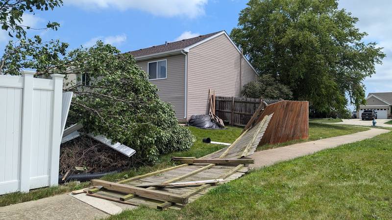 A broken fence lies across a sidewalk on Siegel Drive in Crest Hill, Tuesday, July 16, 2024, after Monday night's storm.