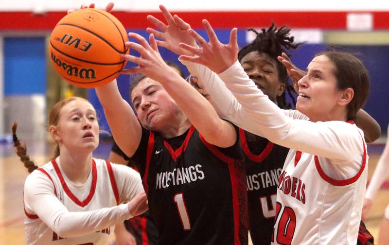 Huntley’s  Alyssa Borzych, right, and Avery Suess, left, tussle with Mundelein’s Madelyn Gardner, center left, and Grace Dunigan, center right, in varsity girls basketball Komaromy Classic tournament  action on Tuesday, Dec. 30, 2025, at Dundee-Crown High School in Carpentersville.