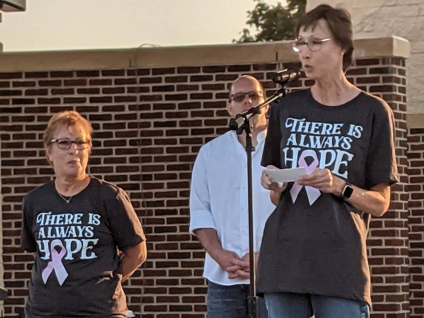 Cancer survivor Cynthia Highfield, right, of Oswego, speaks Oct. 12 at the Pouring For Pink: Breast Cancer Benefit Concert in Oswego. On her left is fellow cancer survivor Lynn Coit. Behind them is Oswego Village President Ryan Kauffman.