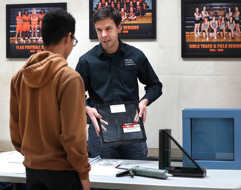 Vince Filicetti, business manager at DeKalb Contract Glazing, talks to an attendee about their products Wednesday, Oct. 22, 2025, during Trades Exploration Day at DeKalb High School. The event hosted several companies and organizations that were offering information on opportunities in the trades.