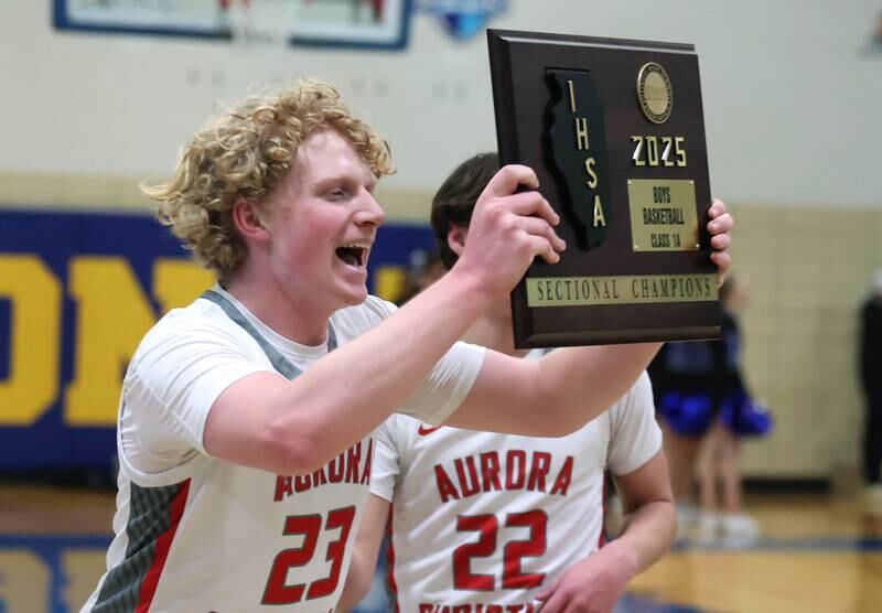 Aurora Christian's Asa Johnson brings the sectional champion plaque to his teammates after their win over Hinckley-Big Rock in the sectional final game Friday, March 7, 2025, at Somonauk High School.